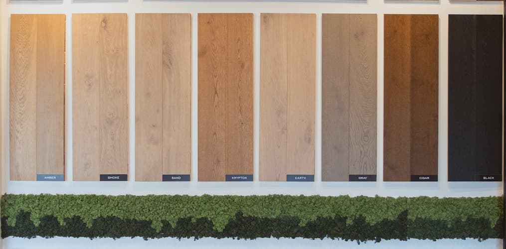 Display of various hardwood flooring samples in different shades from light to dark, labeled from left to right: Smoke, Sand, Krypton, Earth, Gray, Cigar.